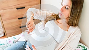 Pregnant pain contractions. Pregnant woman watching clock, holding baby belly. Childbirth time, contractions pain