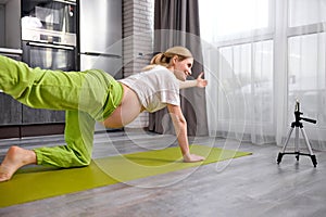 pregnant pleasant lady recording video online translation on mobile phone showing yoga exercises