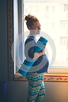 Pregnant red-haired young woman before yoga class