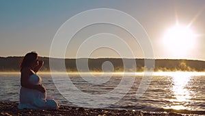 Pregnant Sits On The Lake In The Early Morning And Watch The Sunrise.