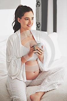 Pregnant, smile and woman with coffee for energy, drink and nutrition or wellness at home on bed to relax. Mother