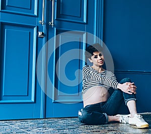 Pregnant smiling woman sitting on wooden floor in room. . Maternity. Motherhood.
