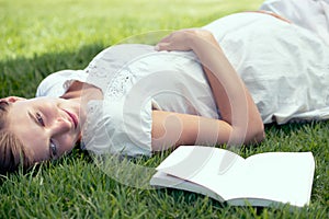 Pregnant, spring and woman reading book in nature outdoor for relax, wellness and peace on field. Pregnancy, literature