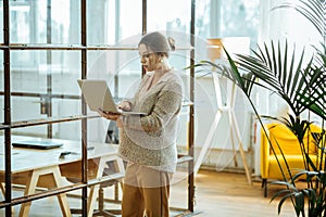 Pregnant successful businesswoman with hair bun holding laptop