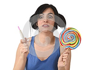 Pregnant teenager holding big lollipop while checking positive pink result on pregnancy test
