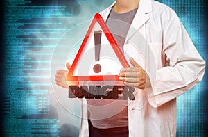 Pregnant white woman scientist holding a red danger triangle warning sign on a blurred blue digital background