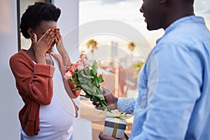 Pregnant, wife and couple with man for surprise, flowers and gift box on balcony or bonding and relationship. Husband