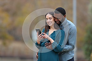 Pregnant wife and her husband checking smart phone