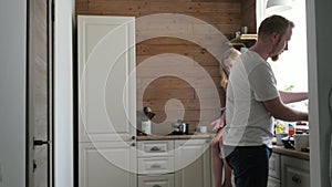 A pregnant wife and her husband have breakfast in the Scandinavian style kitchen. pregnant woman sitting on a table in