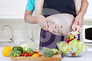 Pregnant wife making salad with her husband