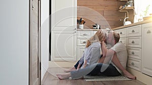 Pregnant wife sitting on the floor with her husband. a man and a pregnant woman are sitting at the back of their kitchen