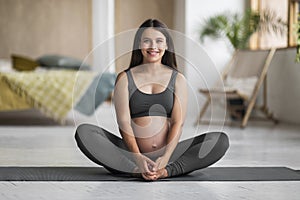 Pregnant Woman In Activewear Sitting On Yoga Mat And Smiling At Camera