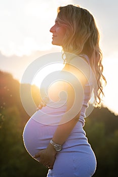 Pregnant woman against setting sun