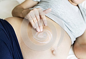 Pregnant woman applying body cream on baby bump