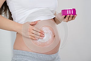 Pregnant Woman Applying Cream On Her Belly