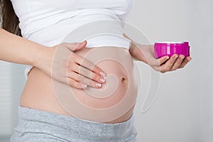 Pregnant Woman Applying Cream On Her Belly