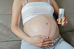 Pregnant woman applying cream at her belly for prevention of stretch marks on the skin