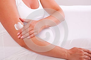 Pregnant woman applying cream on her body