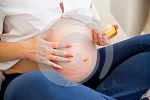 Pregnant woman applying creme on her belly to prevent strech marks