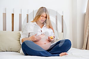 Pregnant woman applying creme on her belly to prevent strech marks