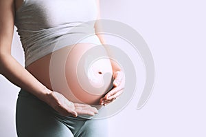 Pregnant woman applying moisturizer cream on her belly. Body skin care during pregnancy