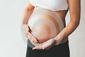 Pregnant woman applying moisturizer on her belly