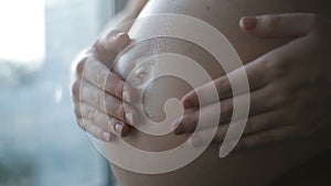 Pregnant woman applying moisturizer on her pregnant belly