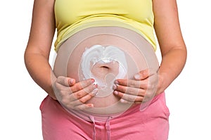 Pregnant woman is applying moisturizing cream on her belly