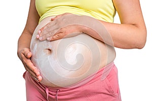 Pregnant woman is applying moisturizing cream on her belly