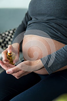 Pregnant woman applying a pregnancy oil