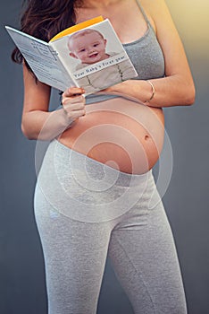Pregnant woman, baby book and belly in studio for maternity and prenatal wellness for pregnancy and motherhood. Young