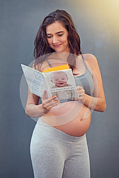 Pregnant woman, baby book and smile in studio for maternity and prenatal wellness for pregnancy and motherhood. Young