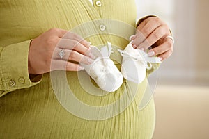 Pregnant woman with baby shoes