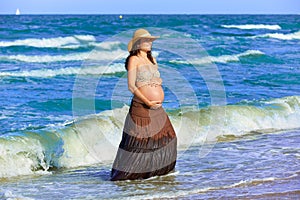 Pregnant woman on the beach with waves