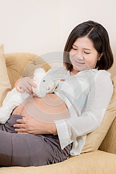 Pregnant woman and bear doll.play with her baby