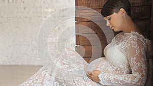 Pregnant woman in a beautiful dress near the window