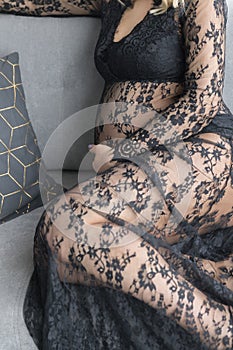 Pregnant woman in a beautiful lace dress holds belly