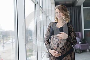 Pregnant woman in a beautiful lace dress holds belly