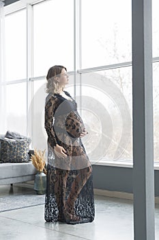 Pregnant woman in a beautiful lace dress holds belly