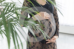 Pregnant woman in a beautiful lace dress holds belly