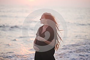 Pregnant woman beauty with long hair walking at the beach.