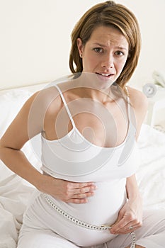 Pregnant woman in bedroom measuring belly