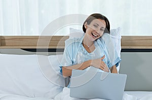 Pregnant woman in bedroom in the morning after waking up she say hello to friends in social media
