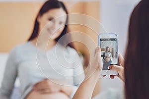 Pregnant woman being photographed by her daughter