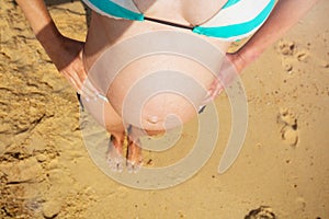 Pregnant woman belly from above stand on beach