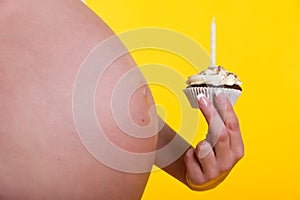 Pregnant woman belly and cake with candle in hand