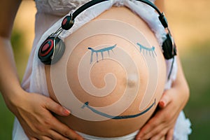 Pregnant woman belly closeup with smiling funny face drawing on