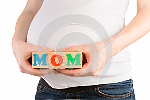 Pregnant woman belly with hands holding colorful wooden blocks with mom sign