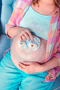 Pregnant woman belly holding baby booties