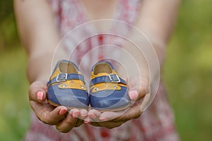 Pregnant woman belly holding baby booties. Healthy pregnancy.